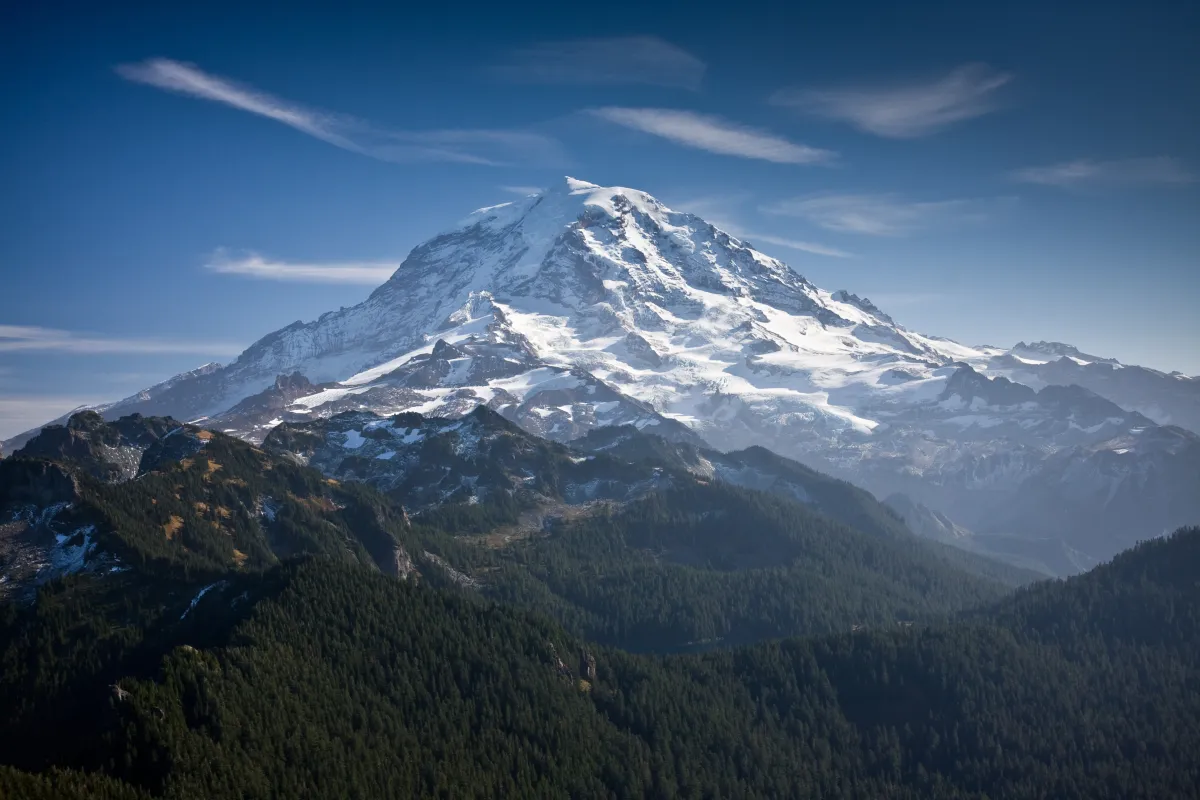 photo of Mount Rainier on a blue sky surrounded by wisps of clouds