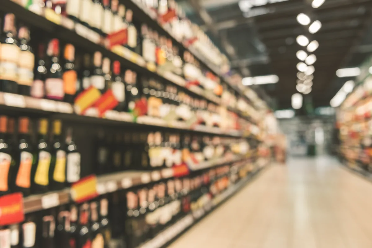 a softly out of focus grocery store aisle filled with wine and liquor bottles