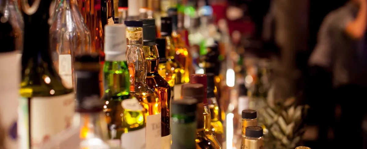 bottles of various types of liquor lined up on the back wall of a bar