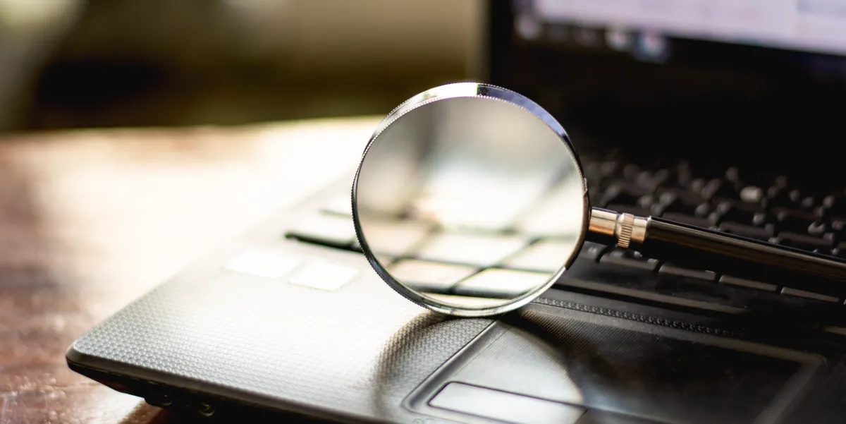 image of a magnifying glass propped up on a black laptop keyboard