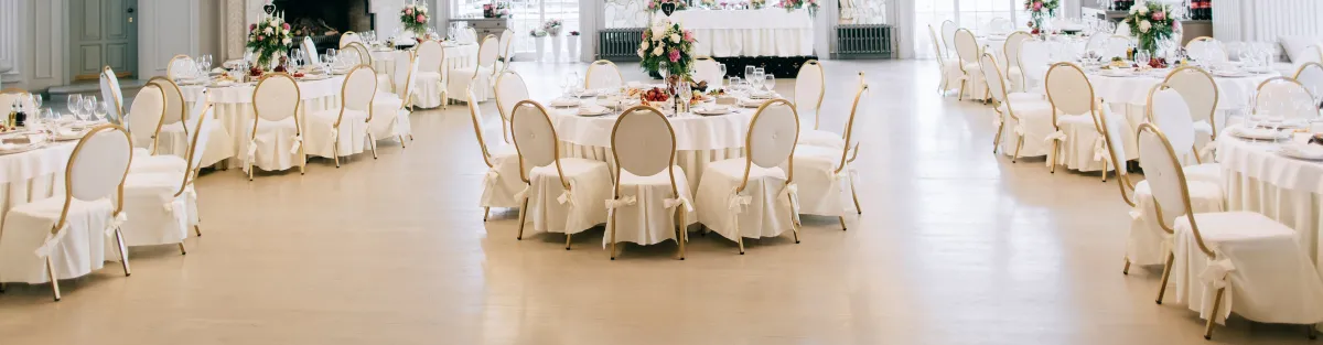 image of circular tables with place settings, white tablecloths and chair covers