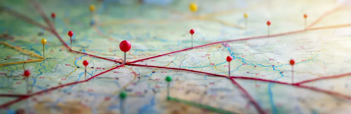 close-up image of a map with red lines and a variety of ball-head pins