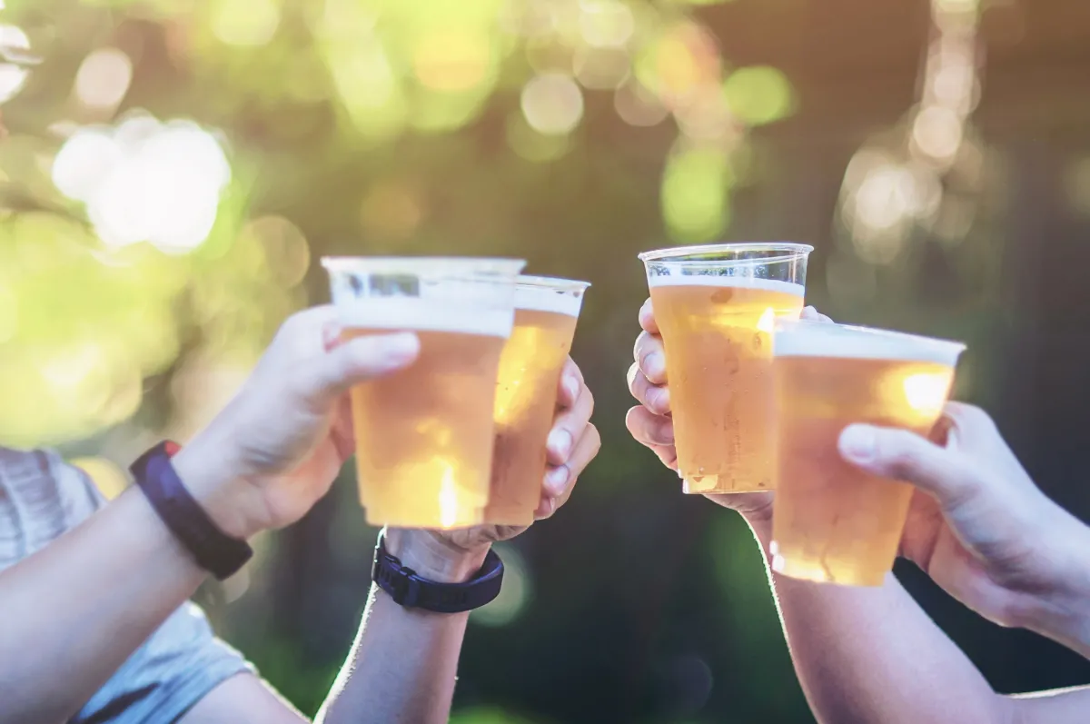 a group of four people holding beer in plastic cups