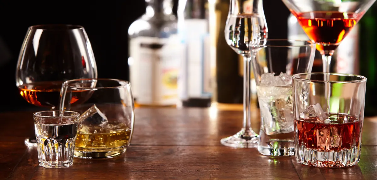 a variety of cocktail glasses with liquor bottles out of focus in the background