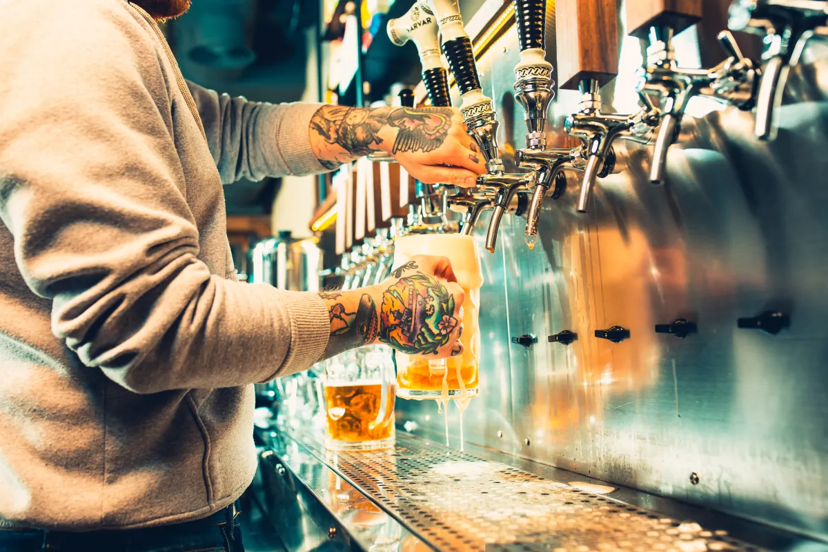 image of a person pouring a glass of beer from a set of taps