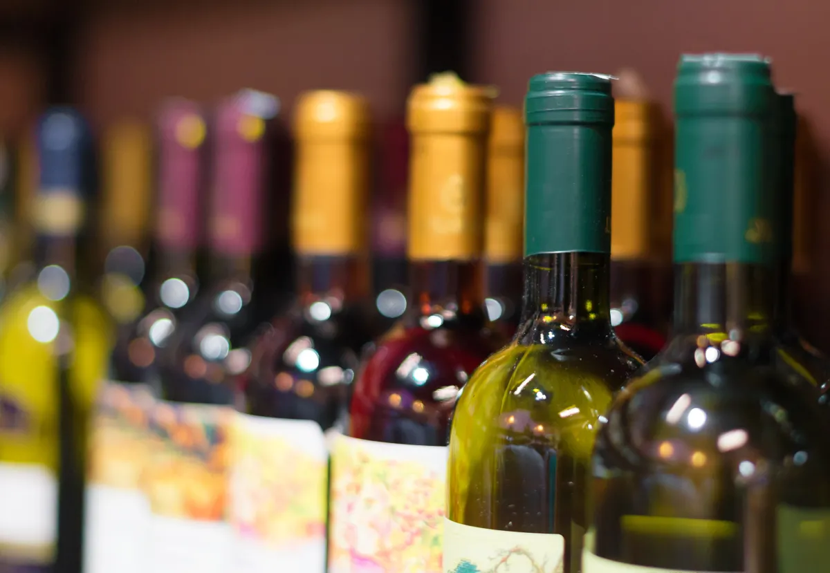 a line of wine bottles with burgundy, gold, and dark green labels