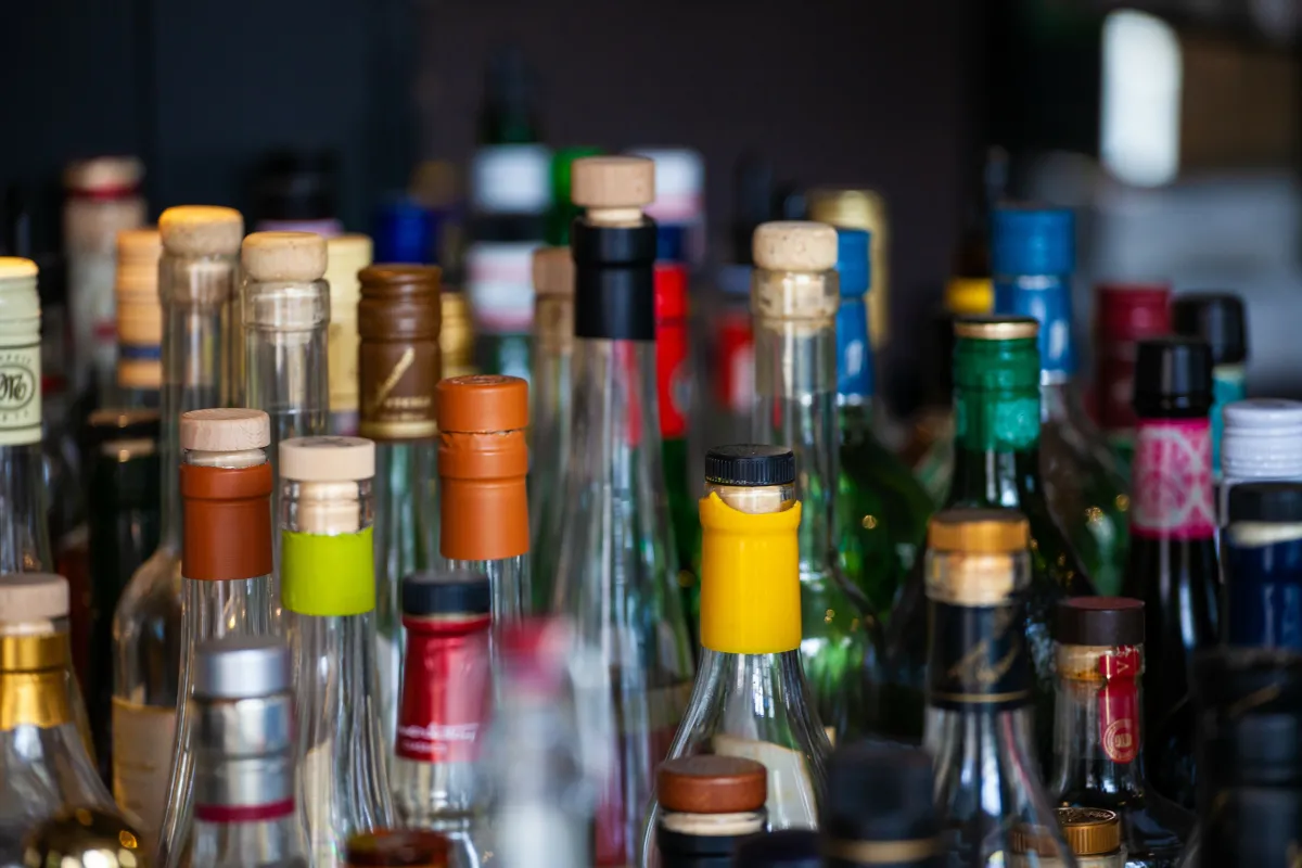 a variety of liquor bottle tops with corks and labels in various colors