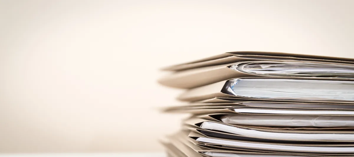 a pile of manila stacked file folders full of papers