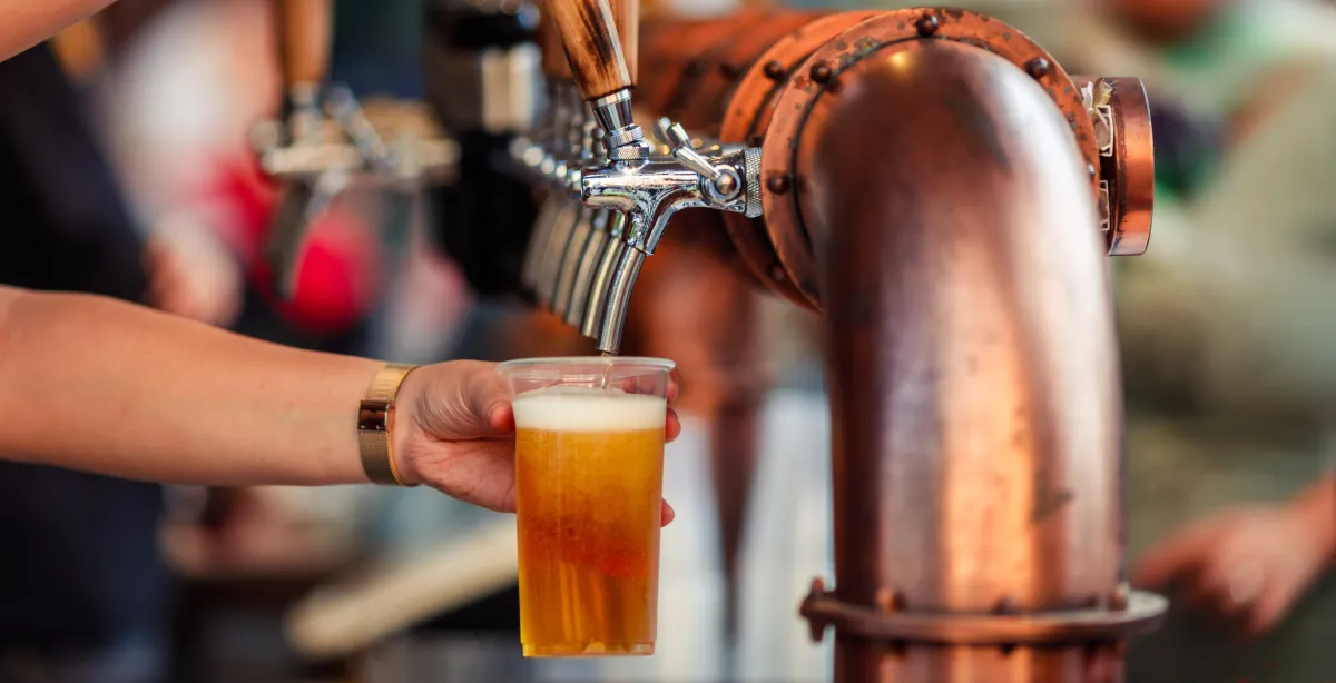 person pouring beer from a tap into a plastic cup