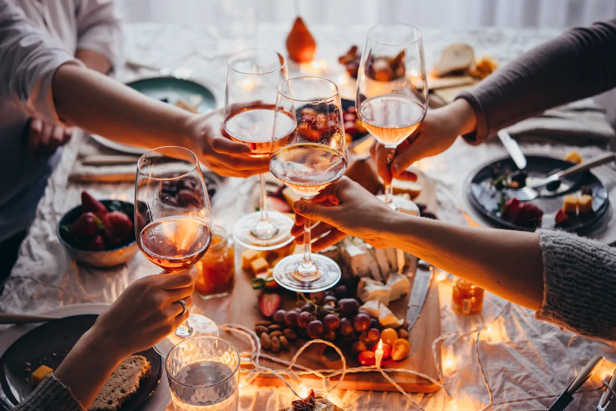 Group of people clinking wine glasses over a dinner table