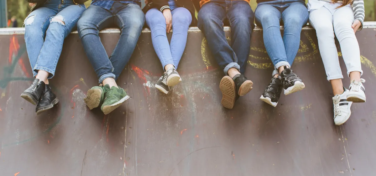 group of teenagers sitting together on a stone ledge