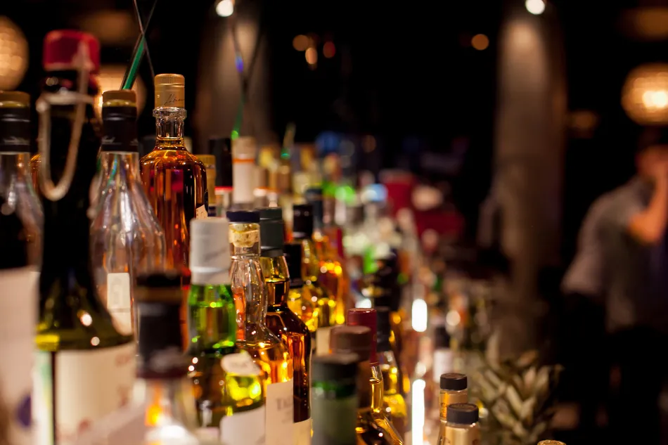 close-up image of spirits and liquor bottles sitting on a bar shelf